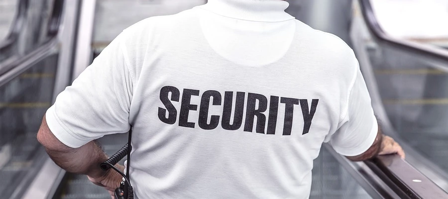 Close-up of the back of a security guard in a mall going down an escalator